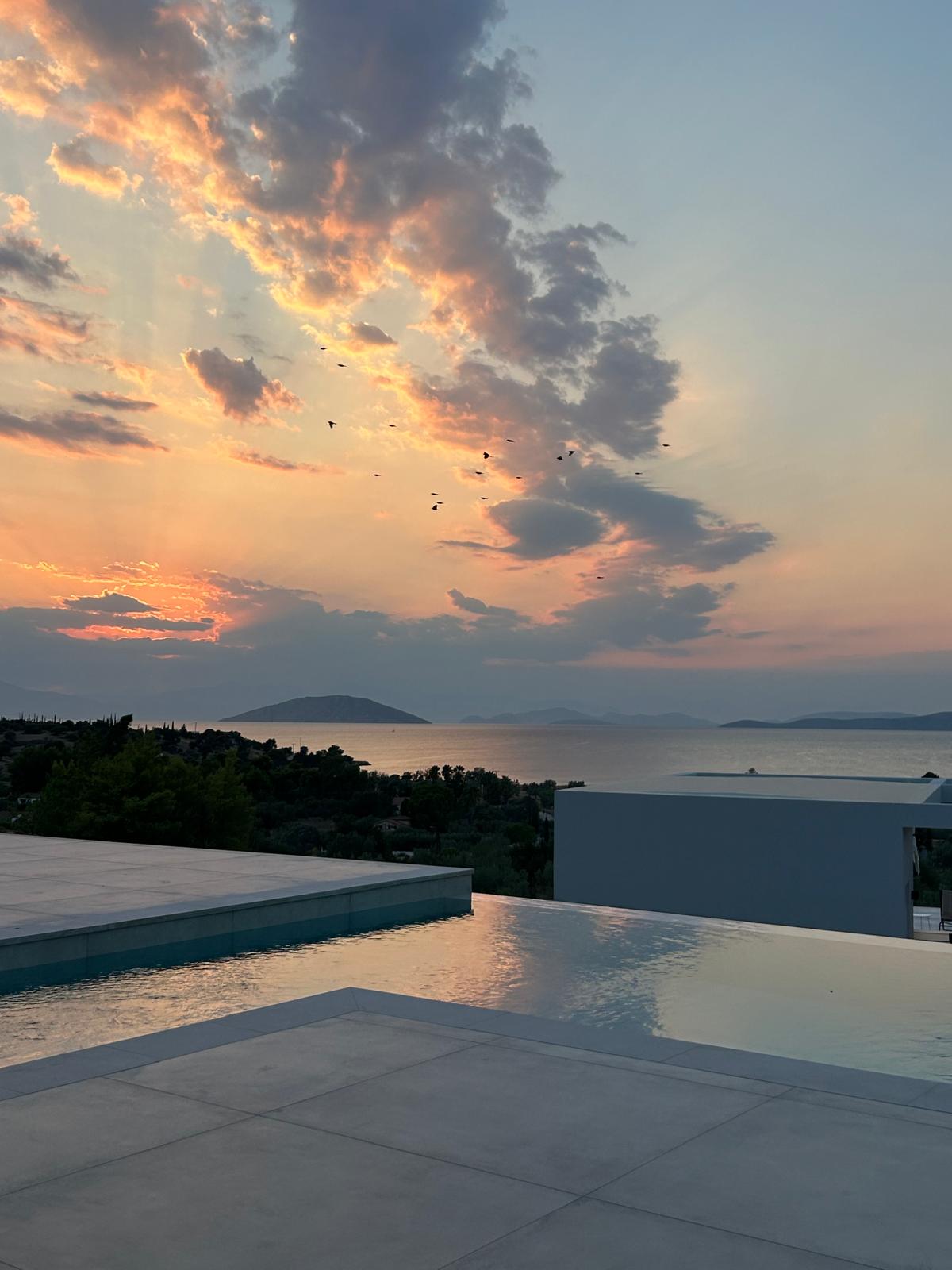 A villa pool terrace above the sea at sunset in Porto Heli