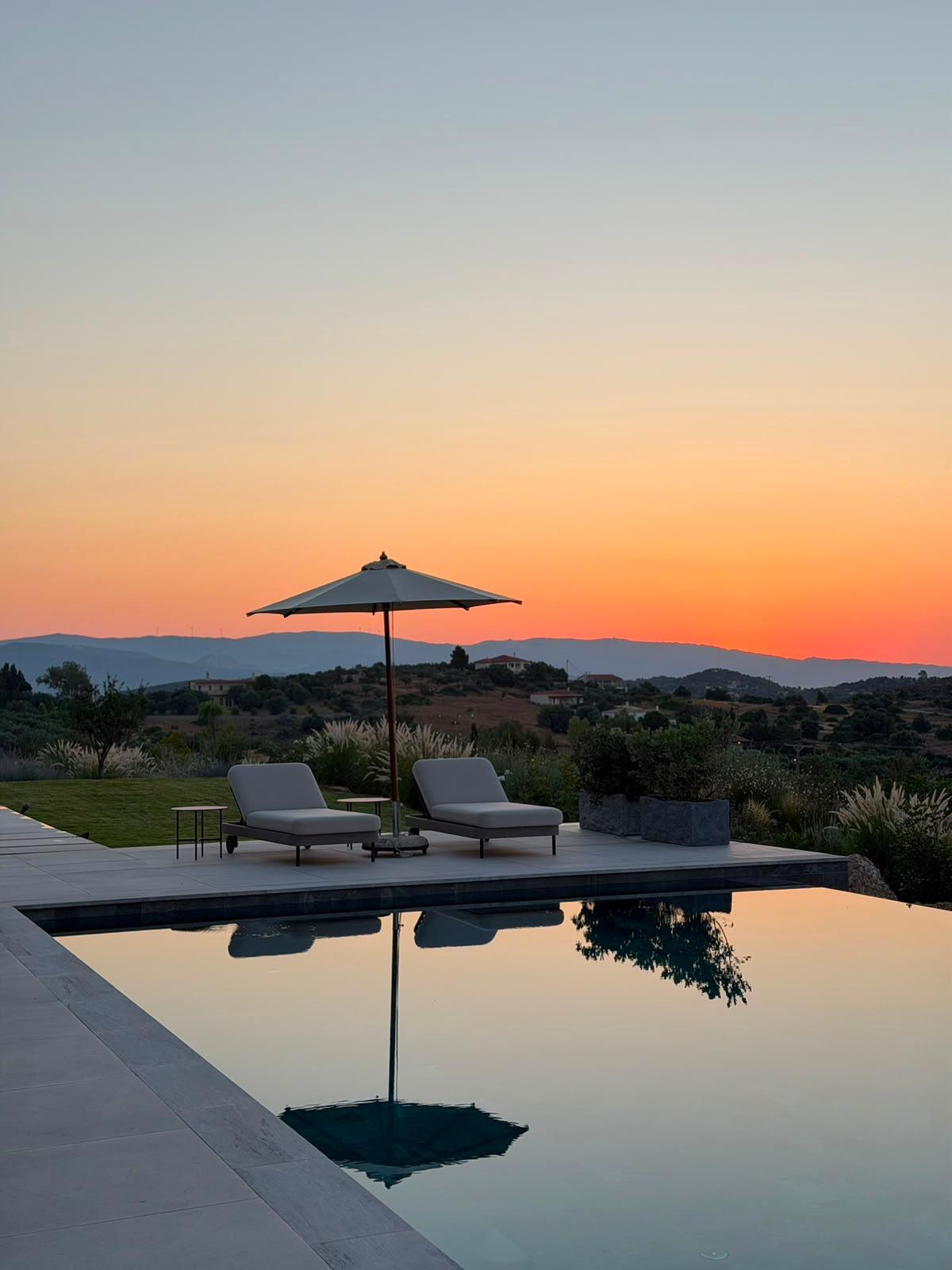 A villa pool terrace with loungers at sunset in Porto Heli